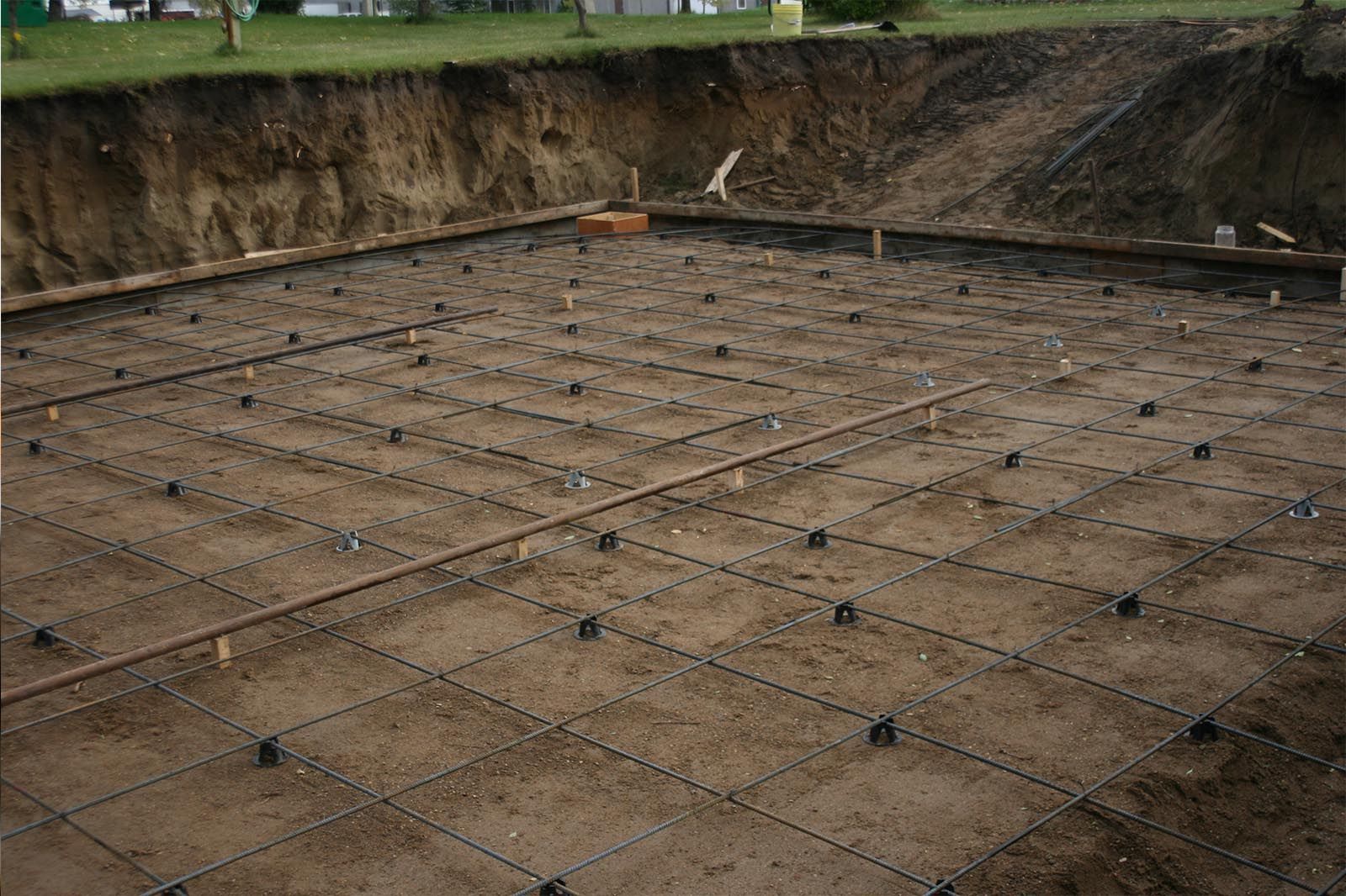 Rebar grid laid over a dirt foundation in a dug-out construction site
