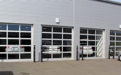 Commercial building exterior with three glass garage doors and parked vehicles inside