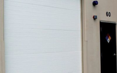 White garage door next to a beige building entrance marked “60” with a black door.