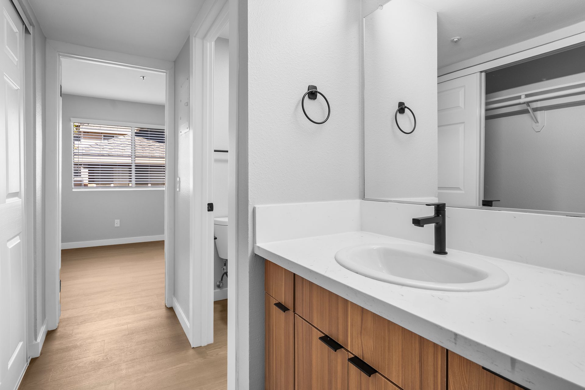 an apartment hallway with wood cabinet and bathroom sink with towel holder