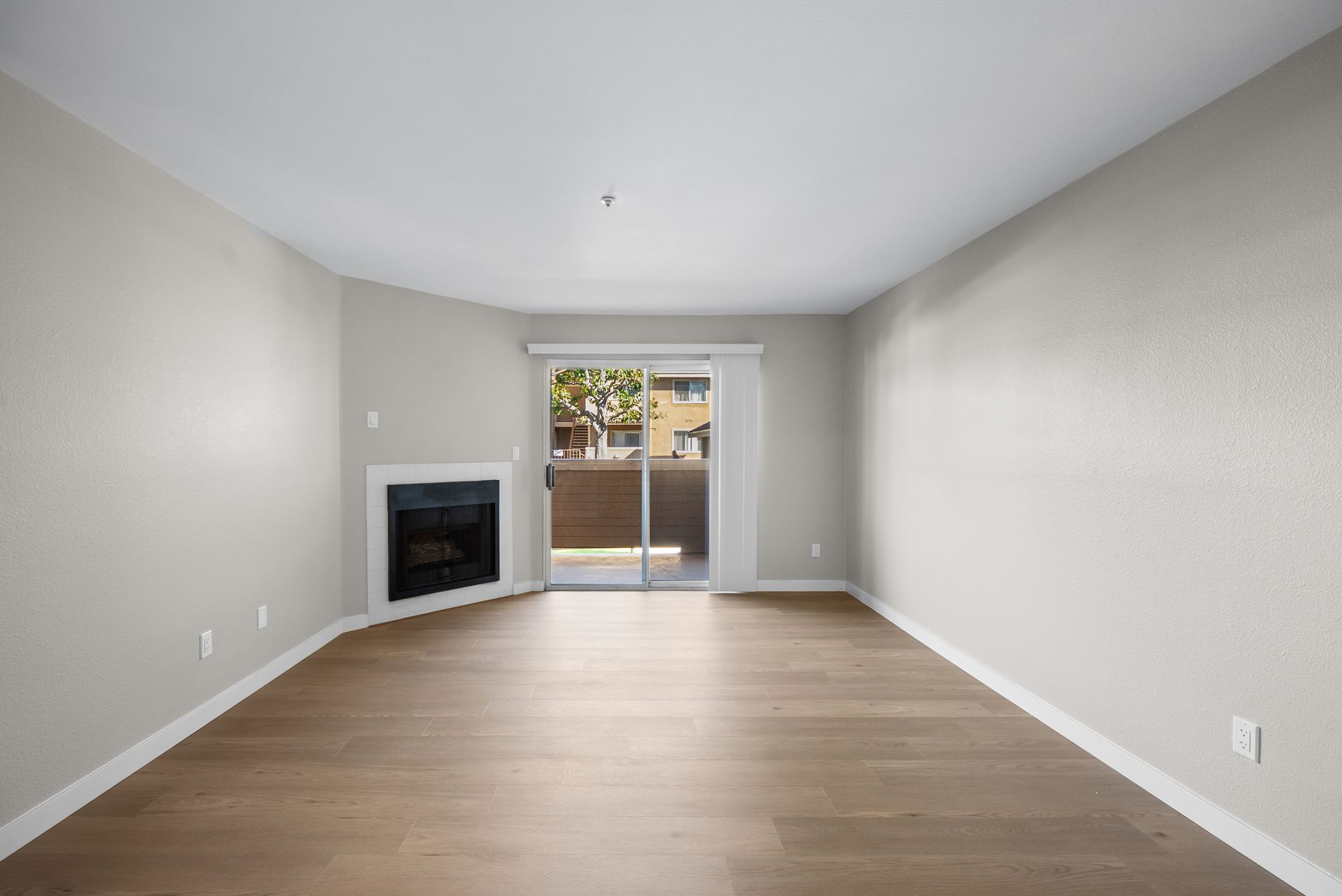 apartment living room at Newhope Village with wood flooring, fireplace, and glass patio door