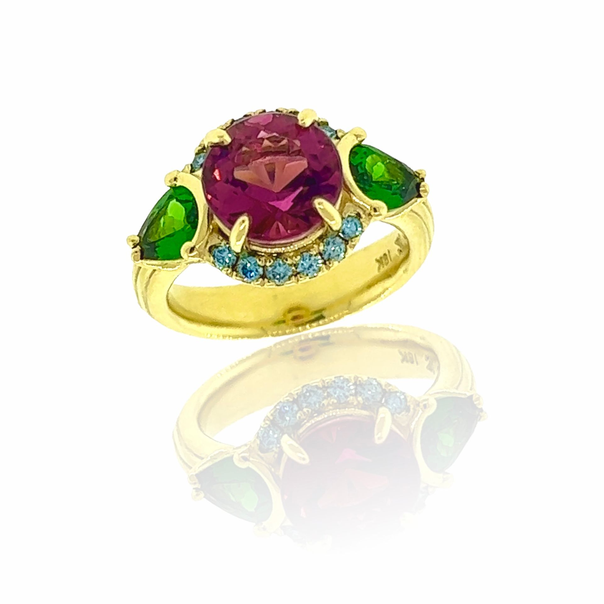 A yellow gold ring with a pink stone and green stones