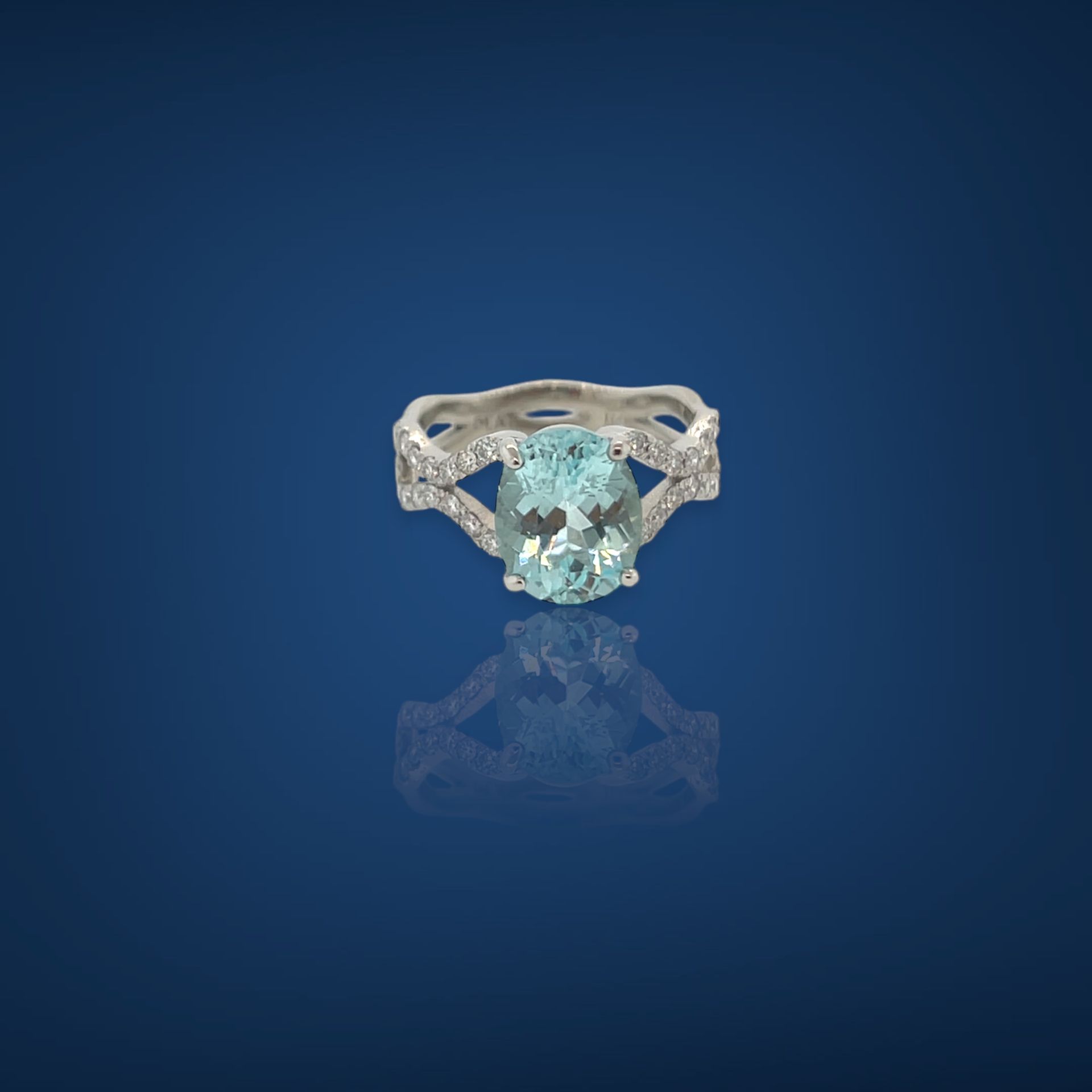 Diamond ring with an oval-cut, light blue gemstone set on a silver band.