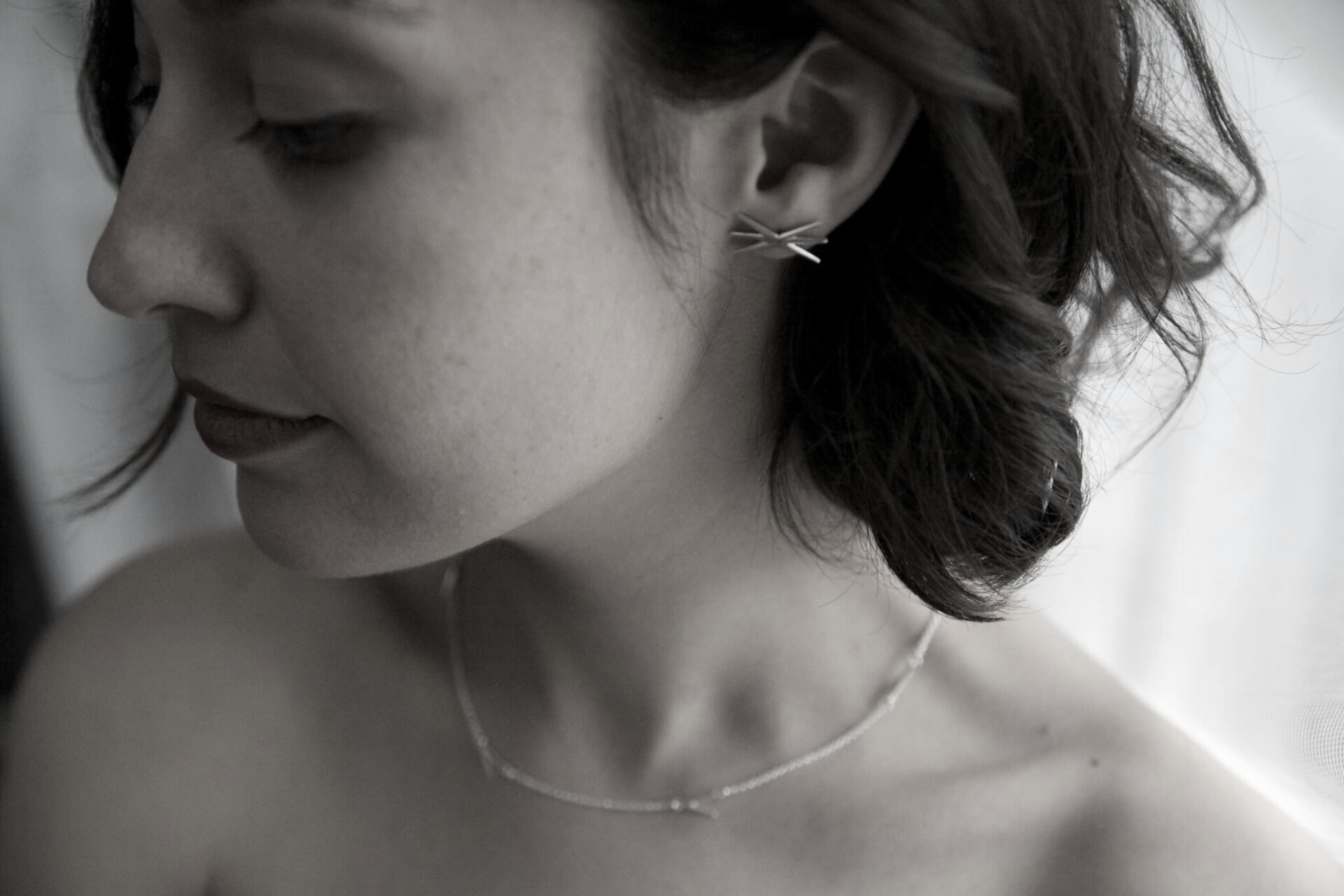 A black and white photo of a woman wearing a necklace and earrings.