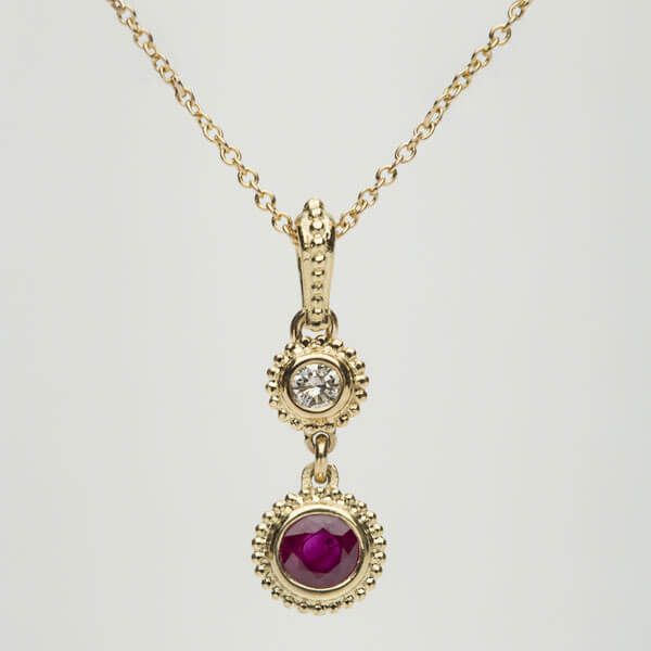 A gold necklace with a ruby and diamond pendant
