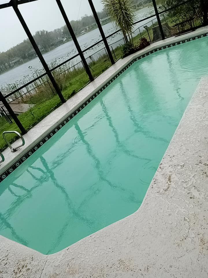 Pool with turquoise water, screened enclosure, and lake view.