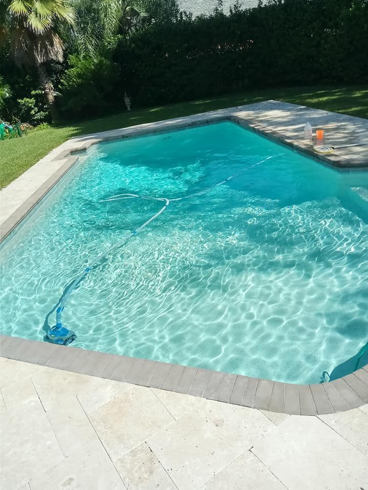 Swimming pool with turquoise water, a pool cleaner, and a sunny outdoor setting.