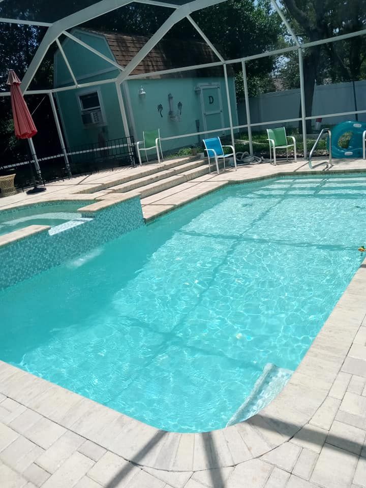 Swimming pool with blue water and steps, surrounded by a white screen enclosure. A red umbrella and chairs are nearby.