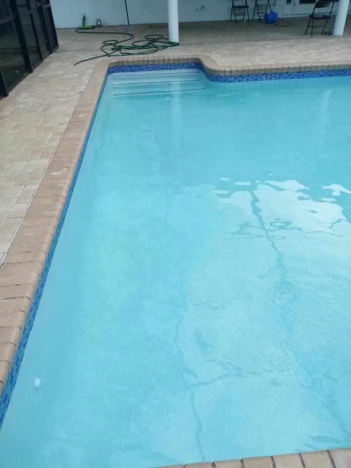 Swimming pool with turquoise water, brick border, and stone deck under a covered patio.