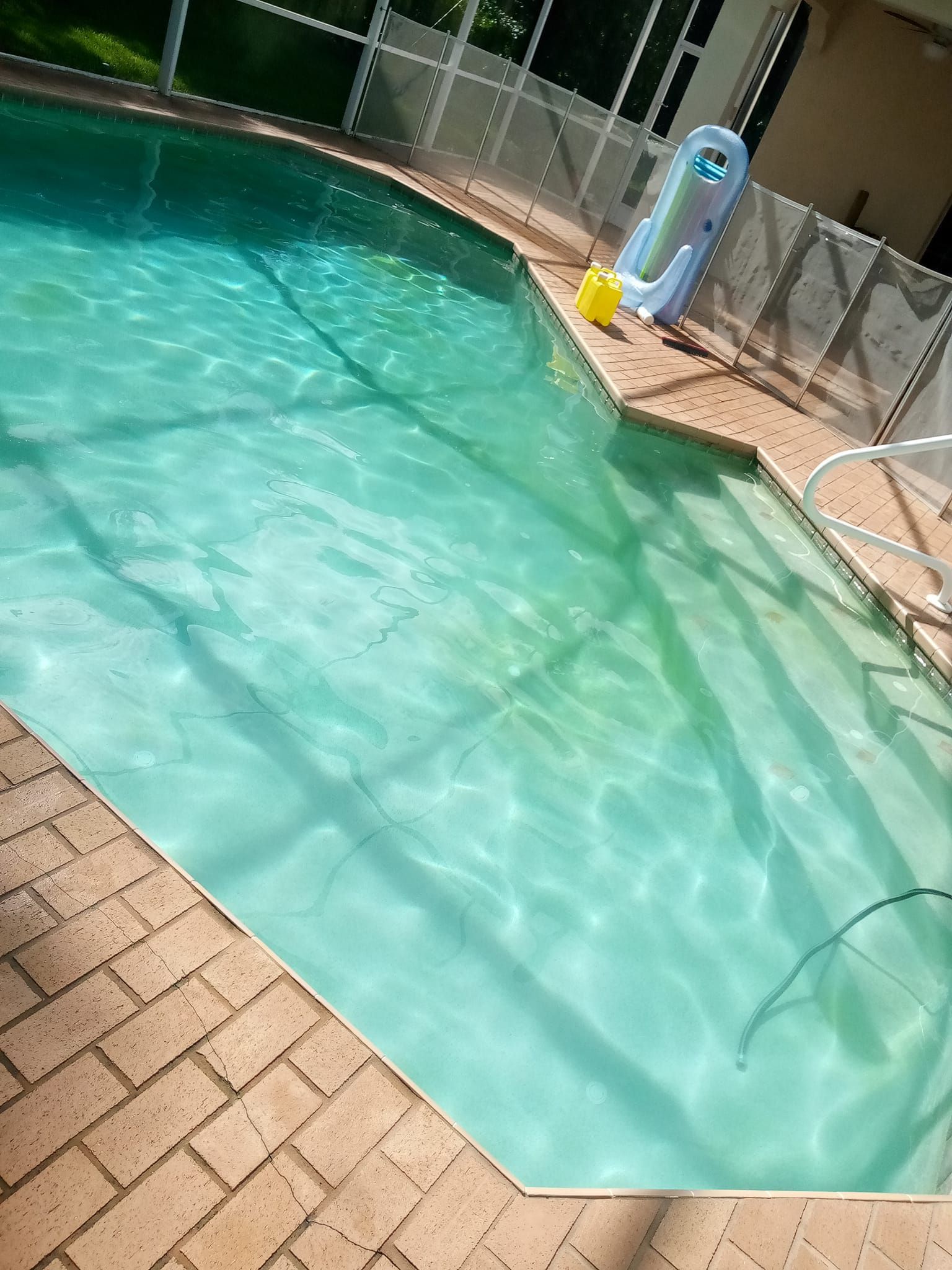 Swimming pool with clear turquoise water and brick patio.