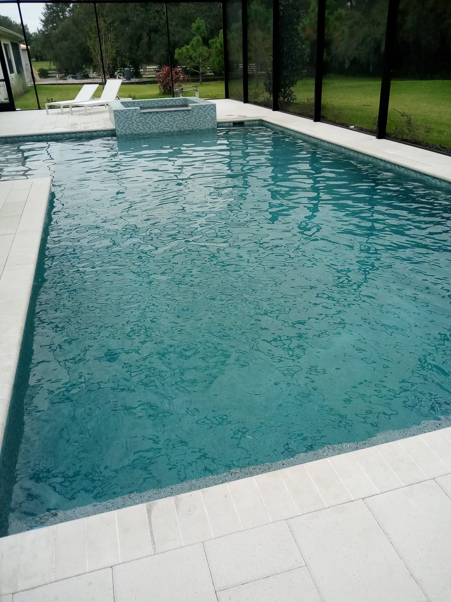 Rectangular swimming pool with light-colored tile surround and a water feature.