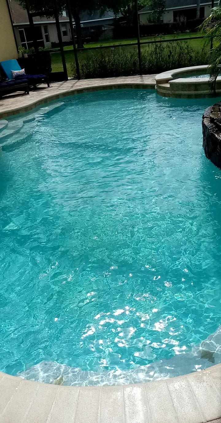 Turquoise pool with stone edging and a small spa.