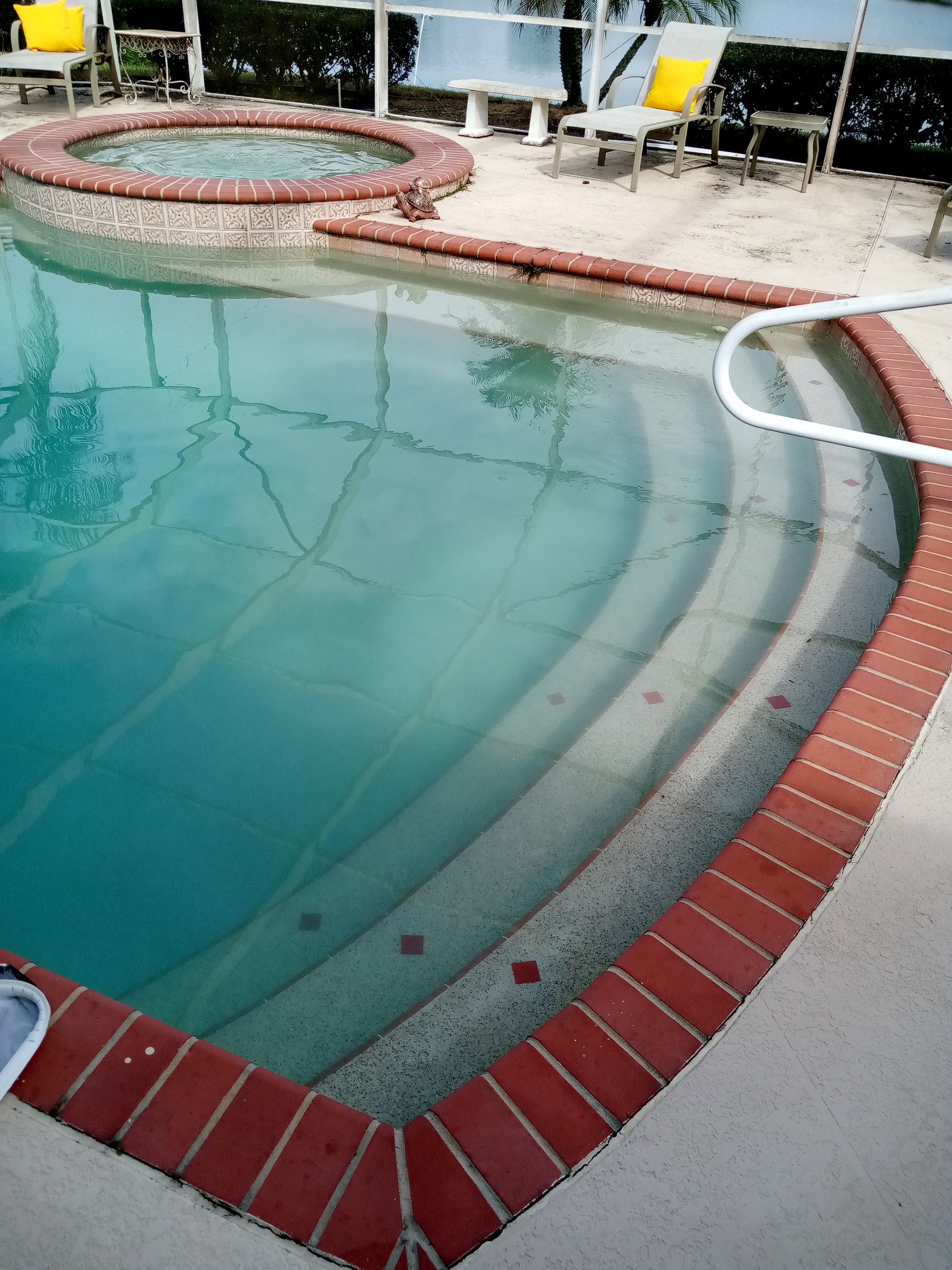 Pool with red brick border, steps, and attached hot tub.