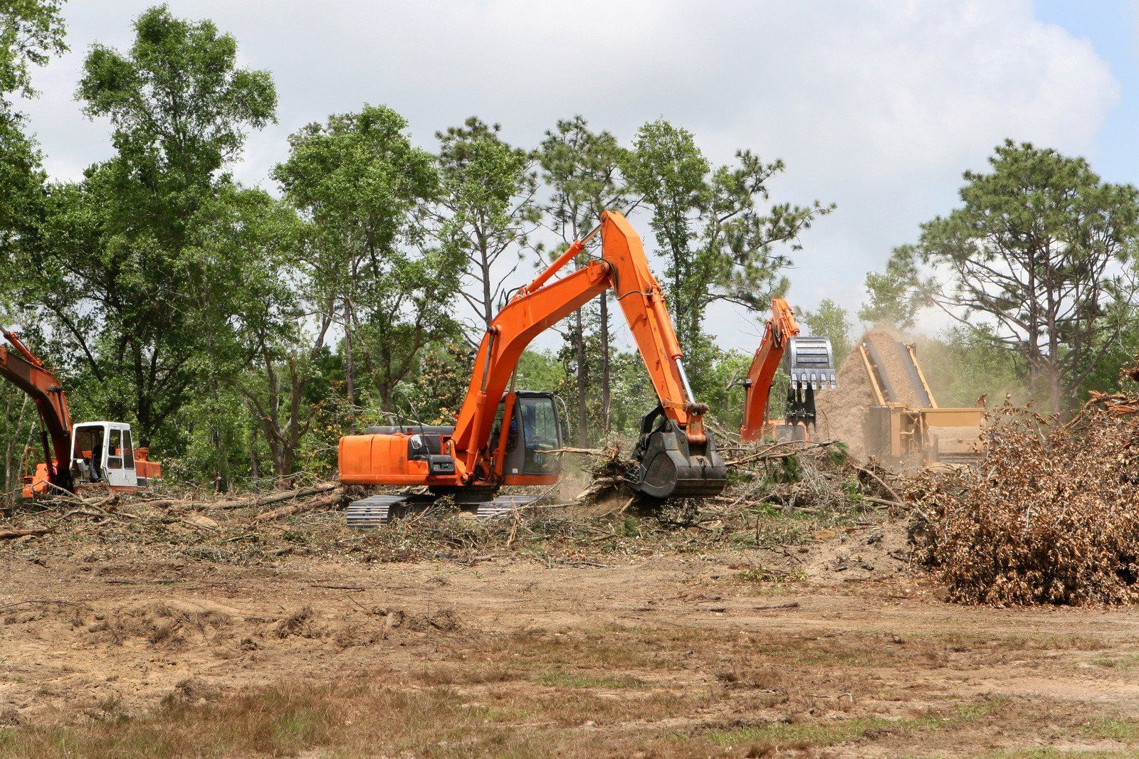 A yellow excavator is sitting on top of a pile of gravel.