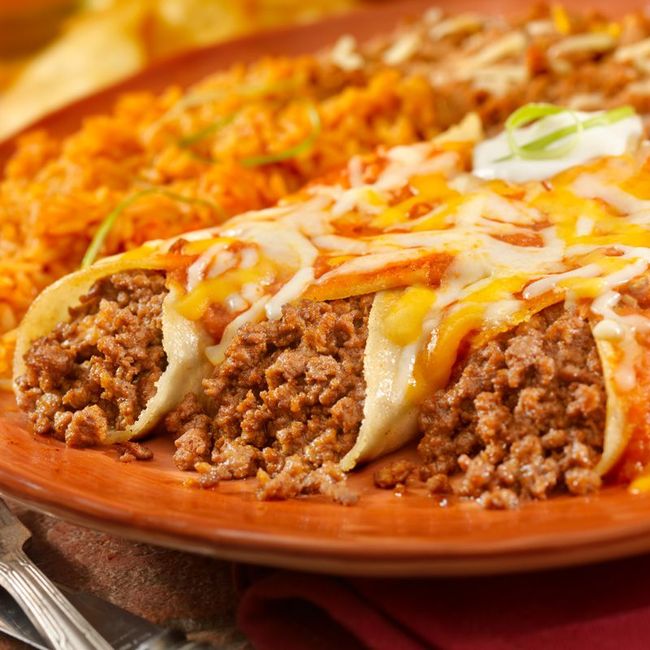 Cheesy beef enchiladas topped with melted sauce on a clay plate