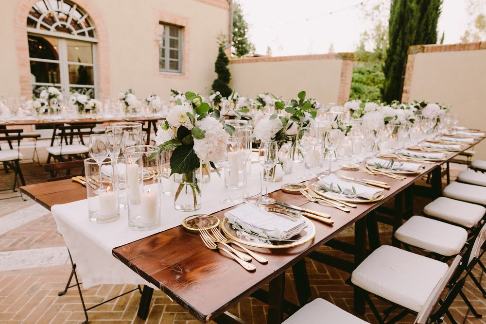 Tavolo da pranzo all'aperto con fiori bianchi, candele e sedie bianche su un patio