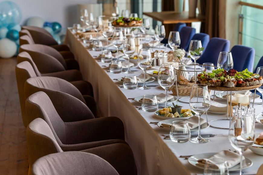 Elegante tavolo da pranzo apparecchiato per un evento formale, con tovaglie bianche, bicchieri e sedie imbottite.