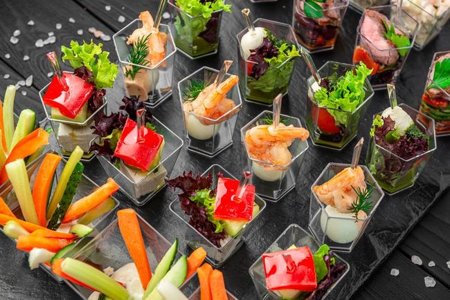 Assortimento di antipasti colorati e crudités di verdure, disposti su un vassoio nero.