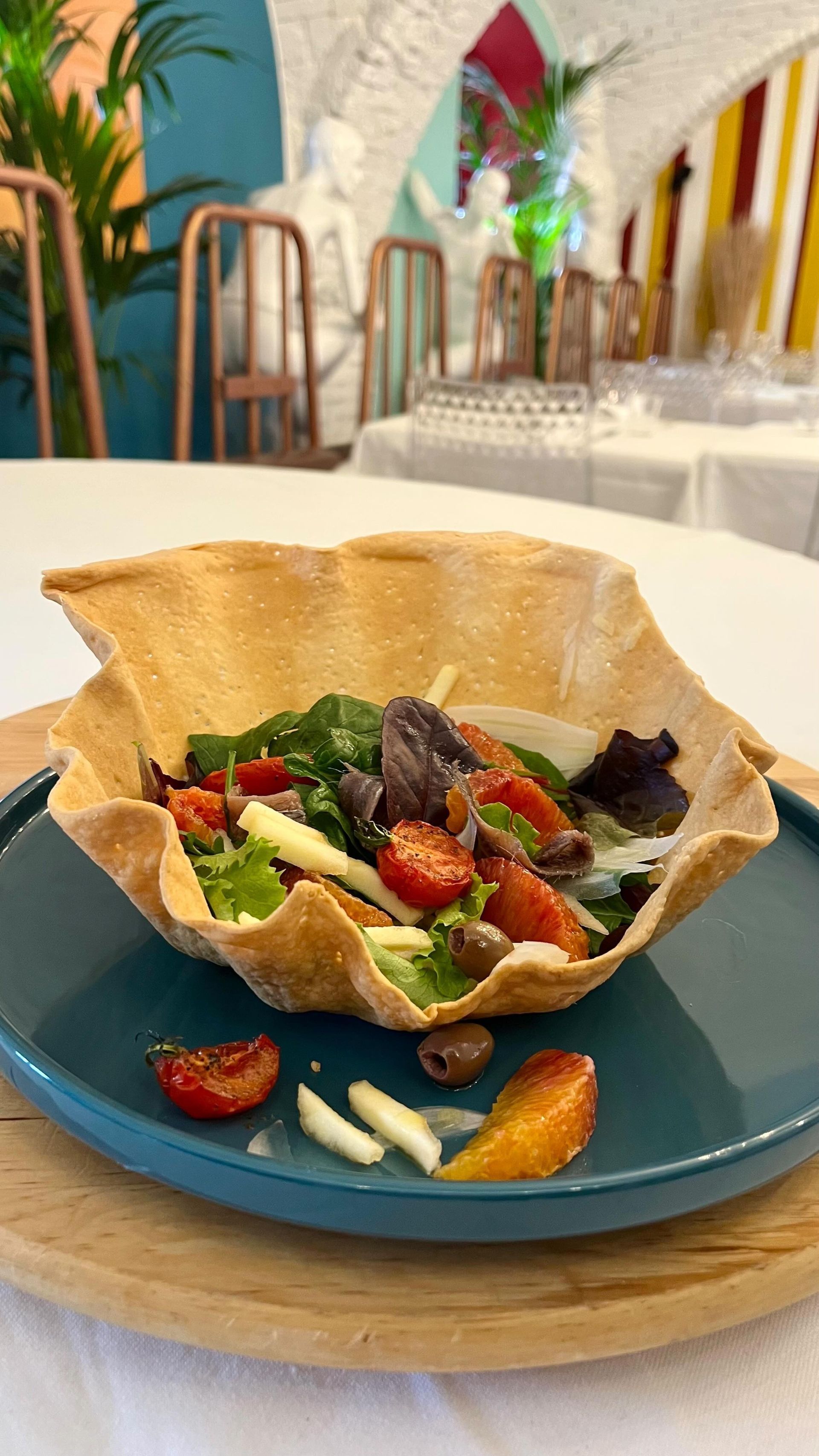 Antipasto gourmet servito in una ciotola di tortilla croccante su un piatto blu, con fragole e verdure, su un tavolo