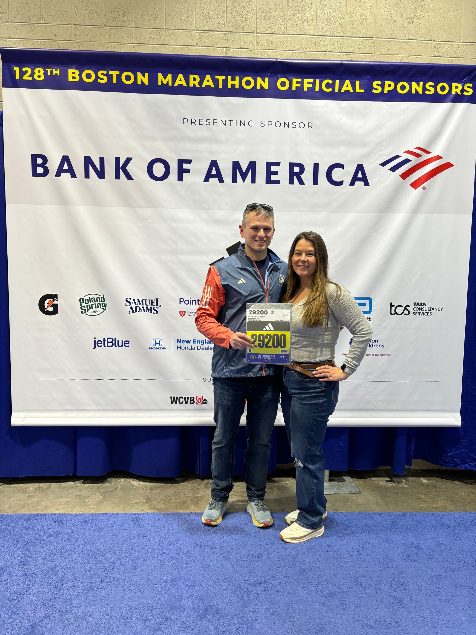 A man and a woman are standing in front of a bank of america banner.