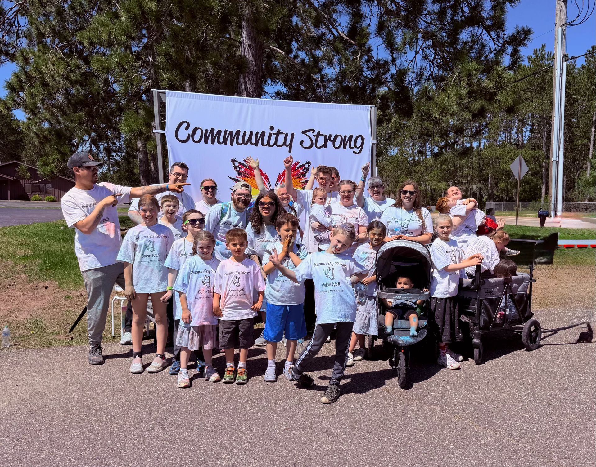 Community group posing outdoors in front of a “Community Strong” banner.