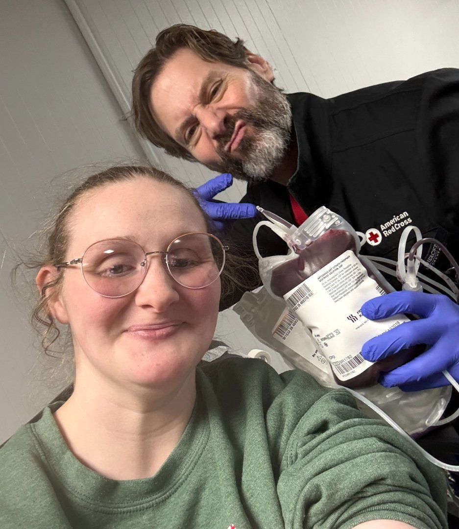 Two people in a lab, one holding a device and container, both wearing gloves and smiling.