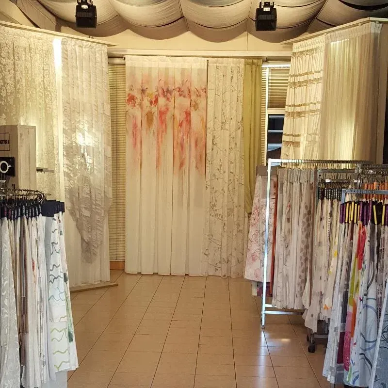 Interno di una boutique di abbigliamento con appendiabiti e una tenda centrale sullo sfondo, illuminato da luci calde.