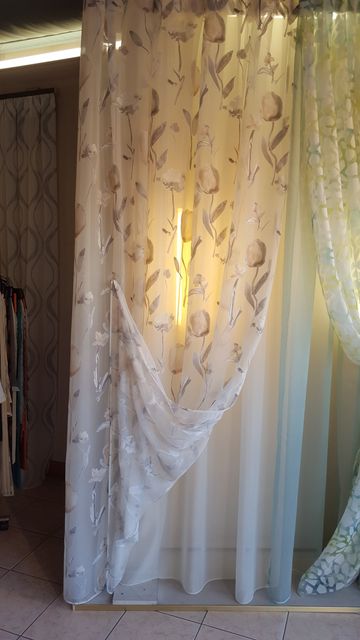 Tende trasparenti con motivi decorativi, dietro le quali filtra una luce calda in una porta.