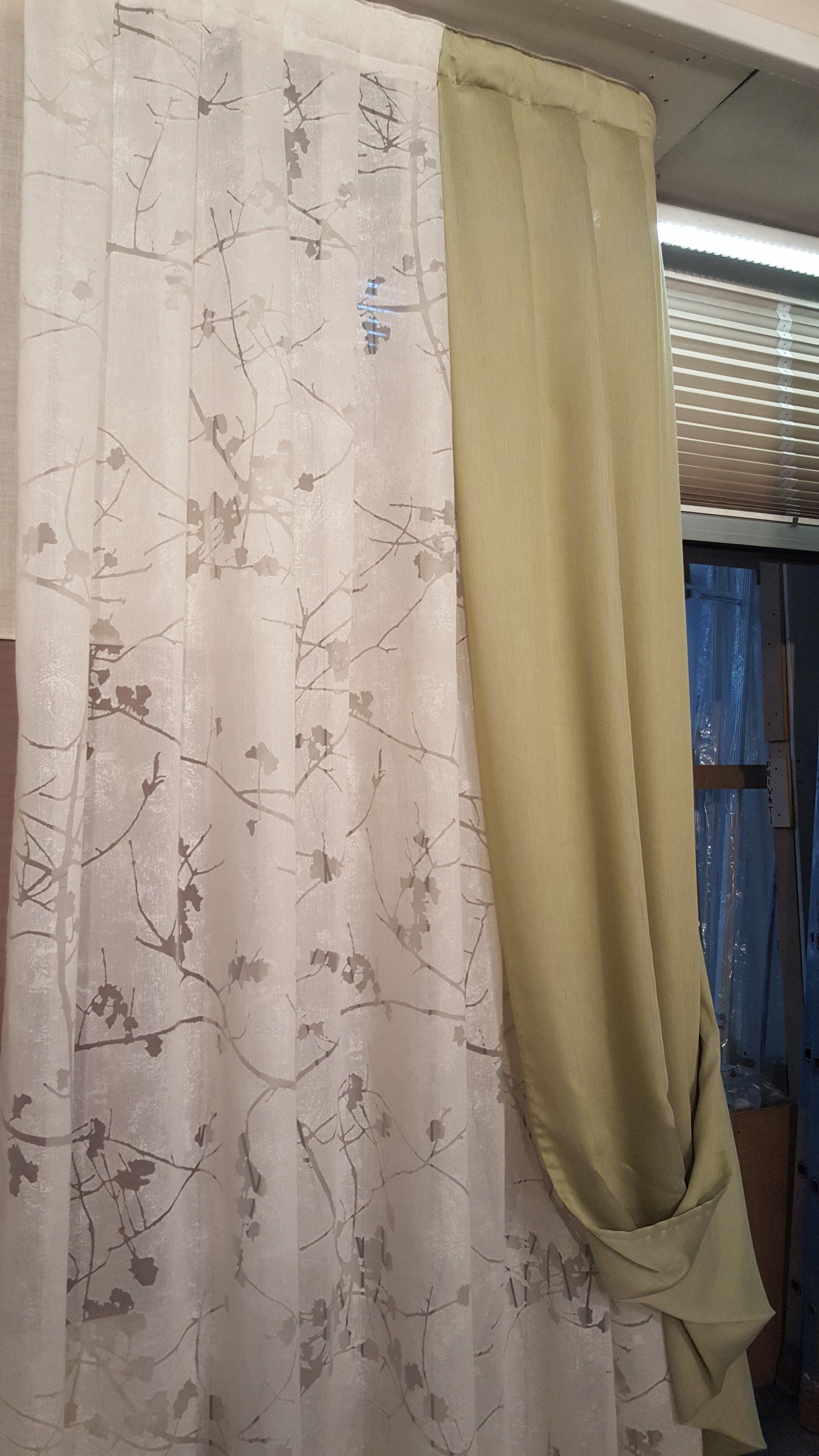 Tenda floreale trasparente accanto a un drappo beige, legato vicino a una finestra