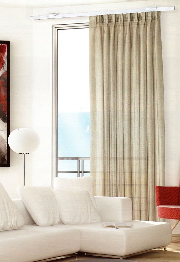 Luminoso soggiorno con divano bianco, lampada da terra, poltrona rossa e tende beige vicino alla finestra.