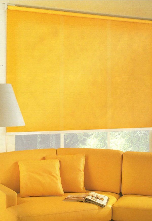 Soggiorno giallo con divano, lampada e grande tenda abbinati.