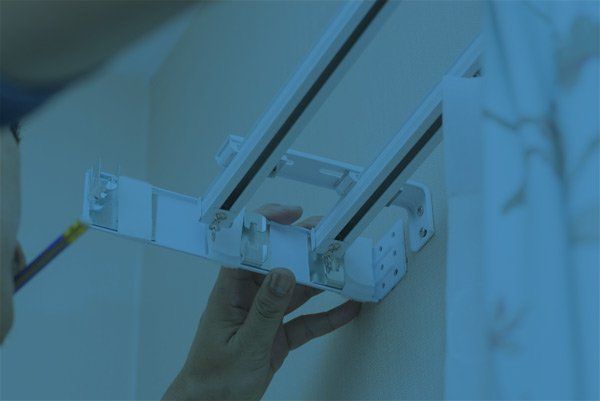 Installazione manuale di un apparecchio o staffa a parete di colore bianco con binario metallico e viti.