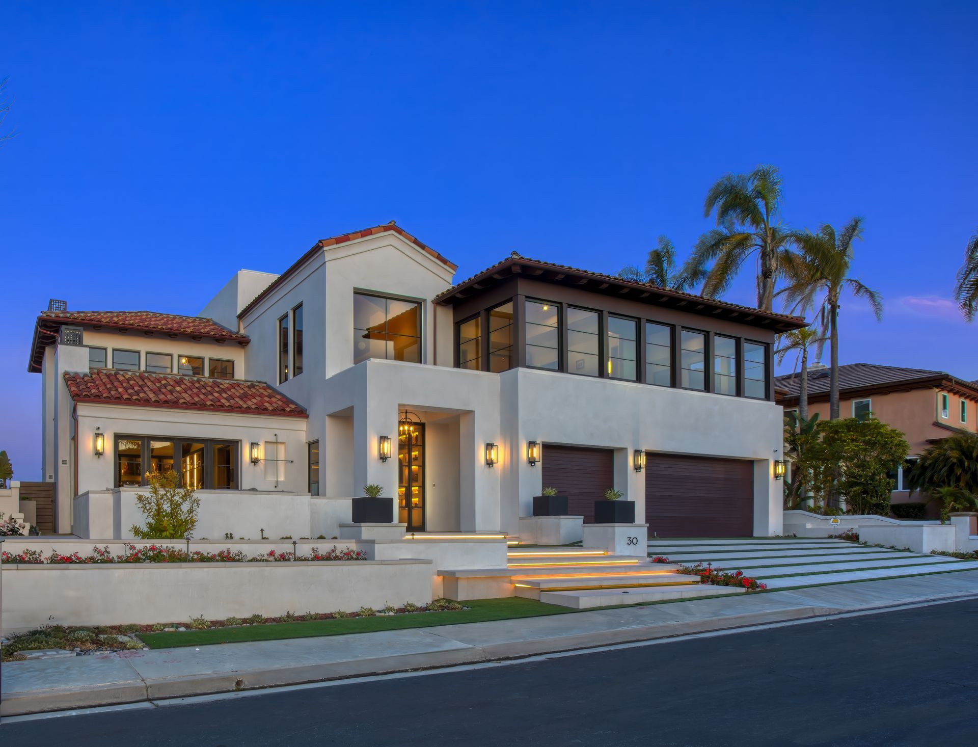 A large white house with a red tile roof is sitting on the side of the road.