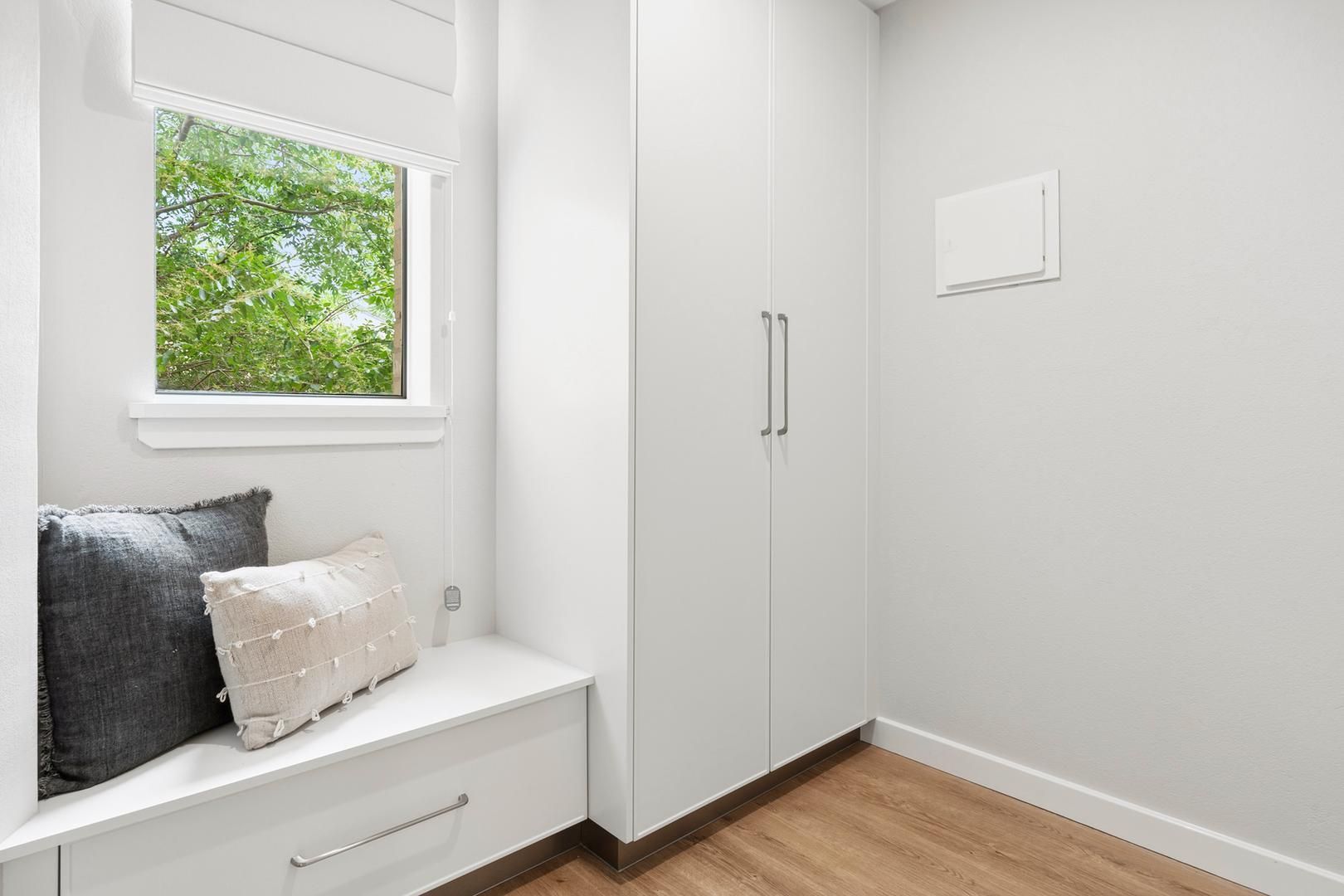 A laundry room with a window seat and a window.