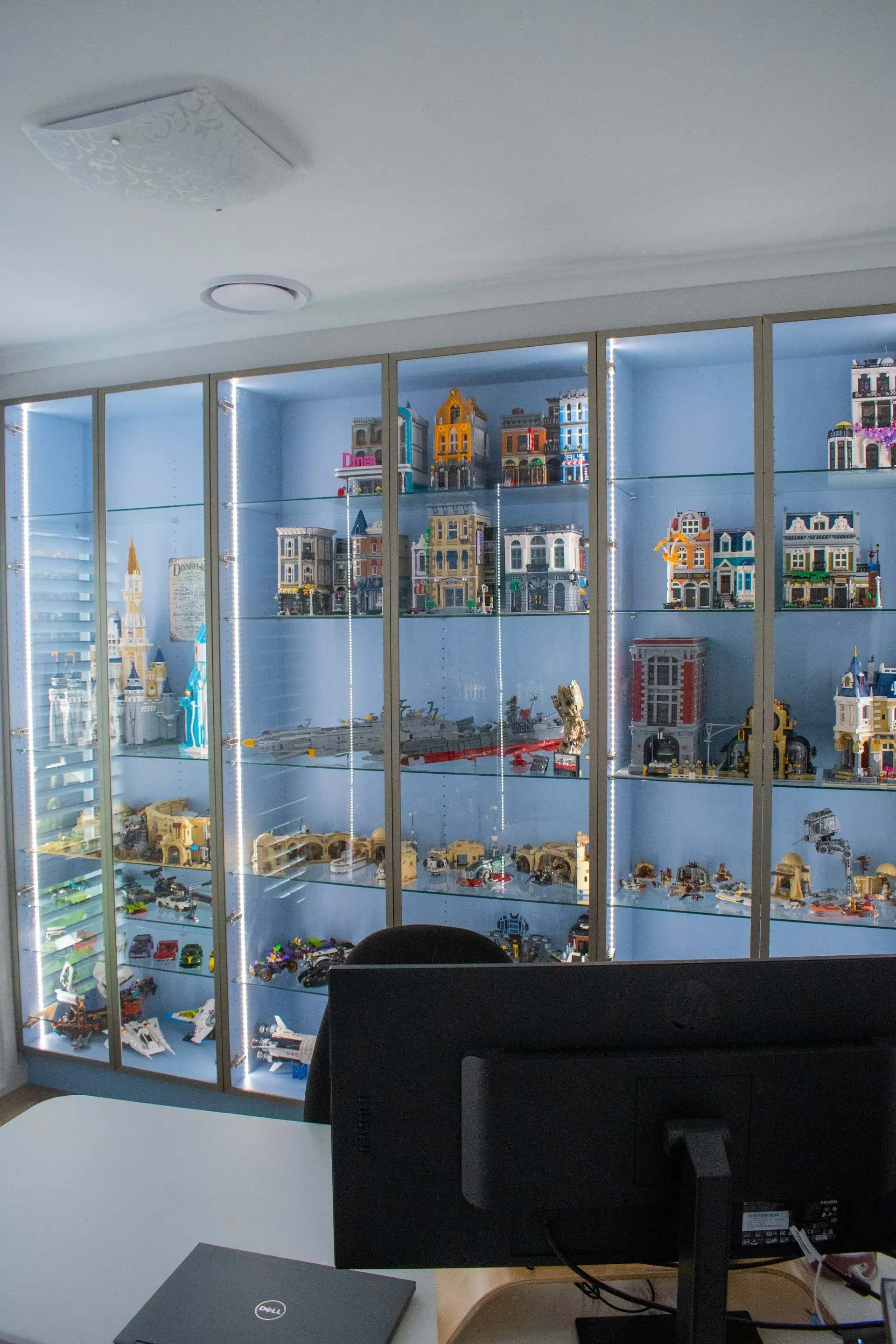 A computer monitor sits in front of a display case filled with lego buildings.