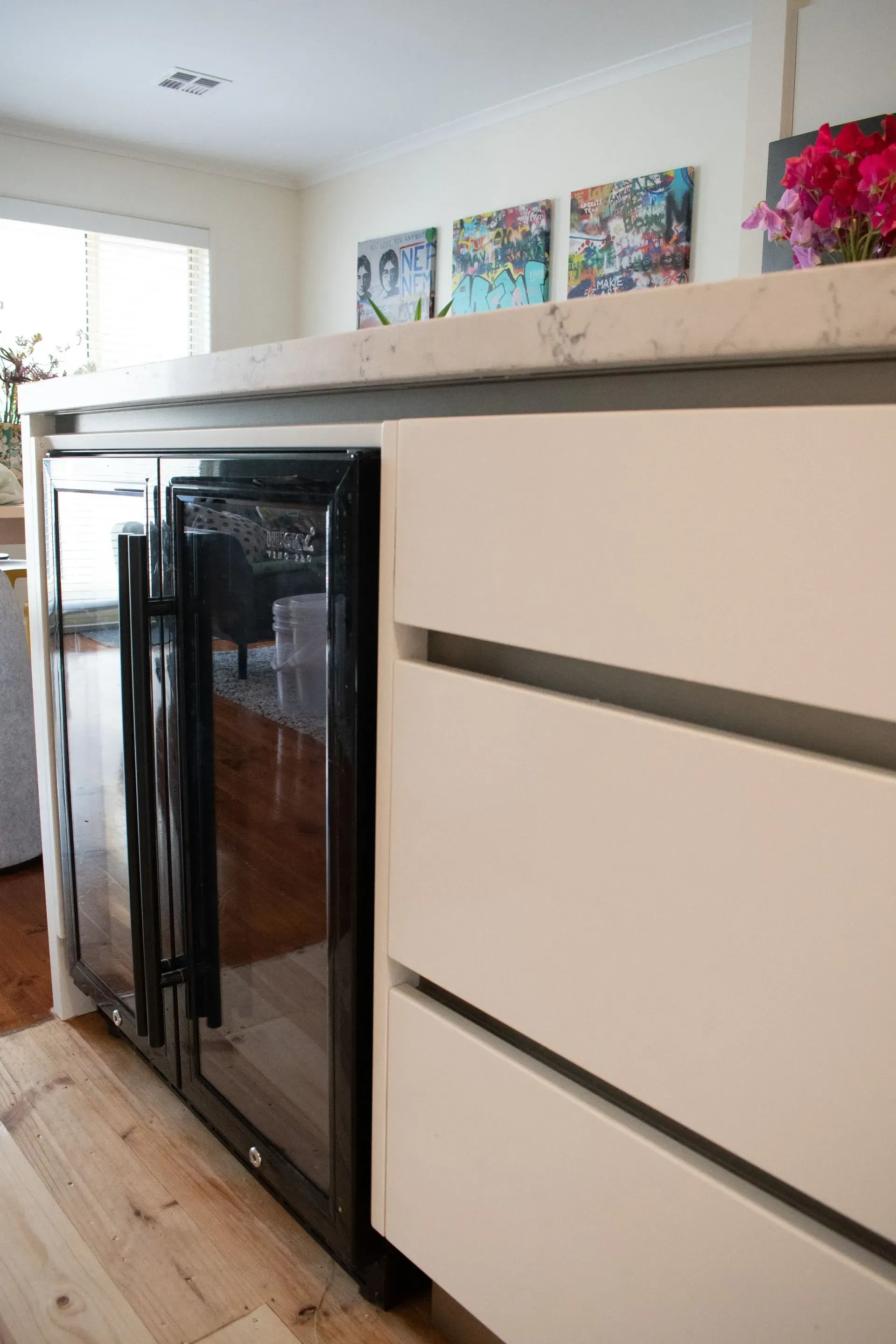A kitchen with white cabinets and a wine cooler.