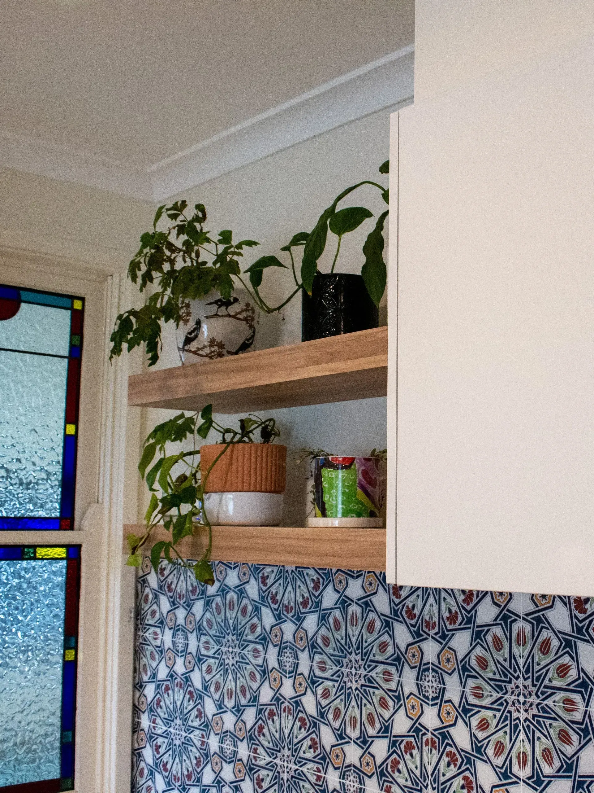 A shelf with potted plants on it next to a stained glass window