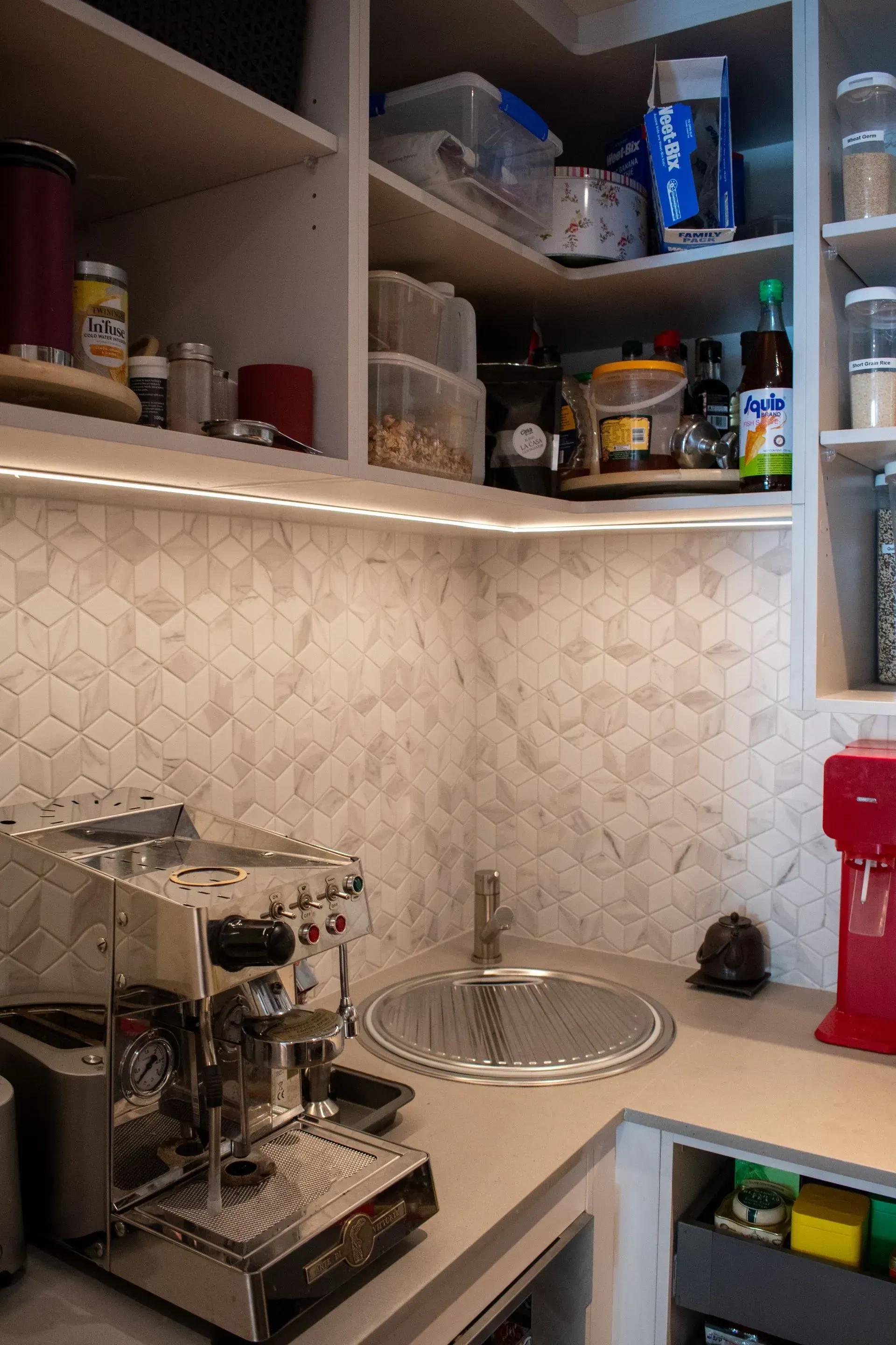 A kitchen with a coffee machine and a sink.