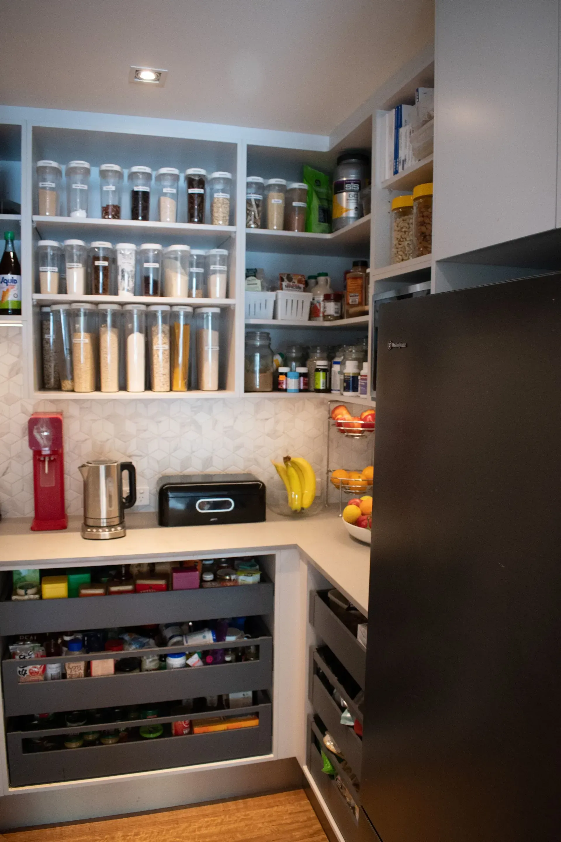 A kitchen with lots of shelves and drawers and a refrigerator.
