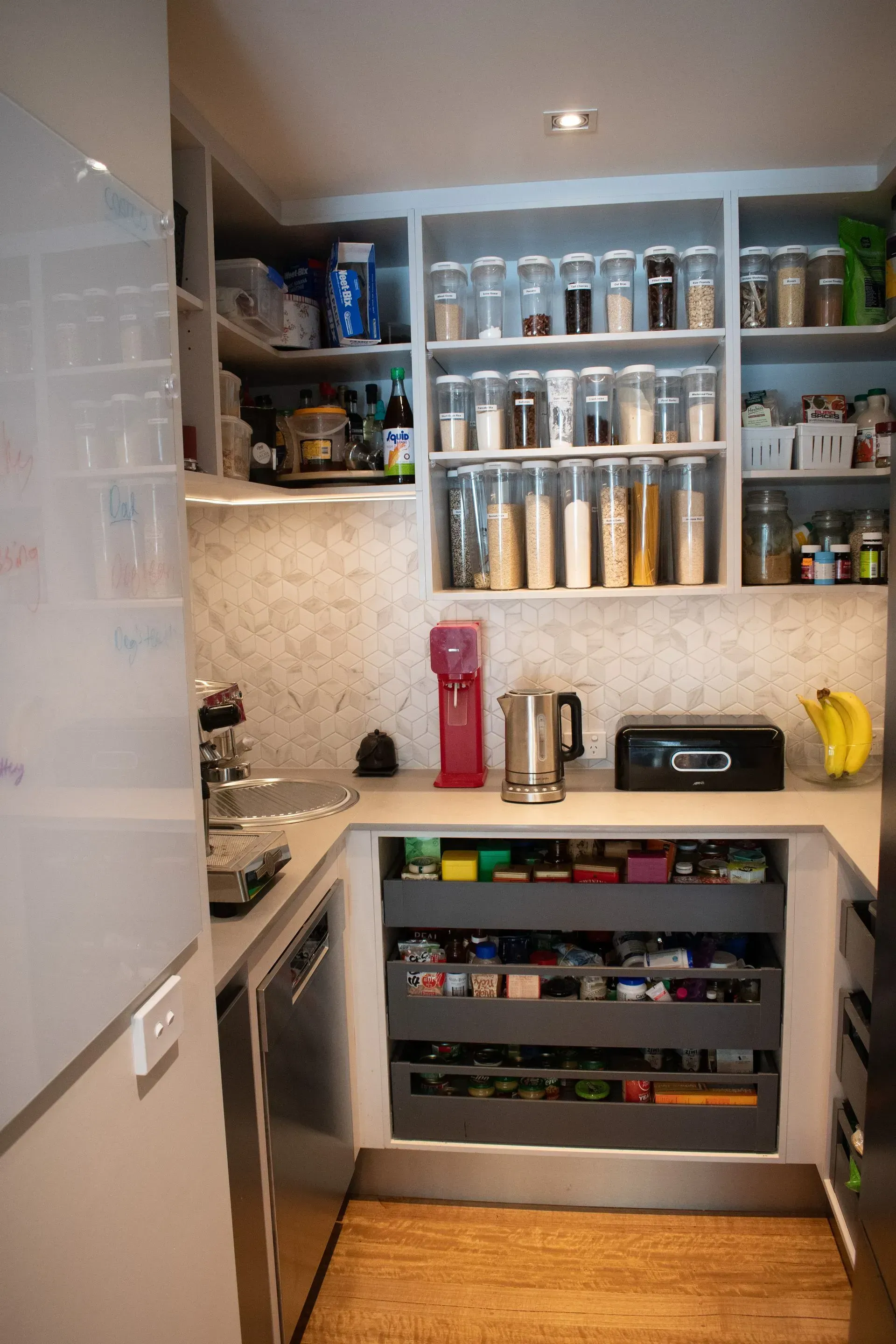 A kitchen with a lot of shelves and drawers filled with food.
