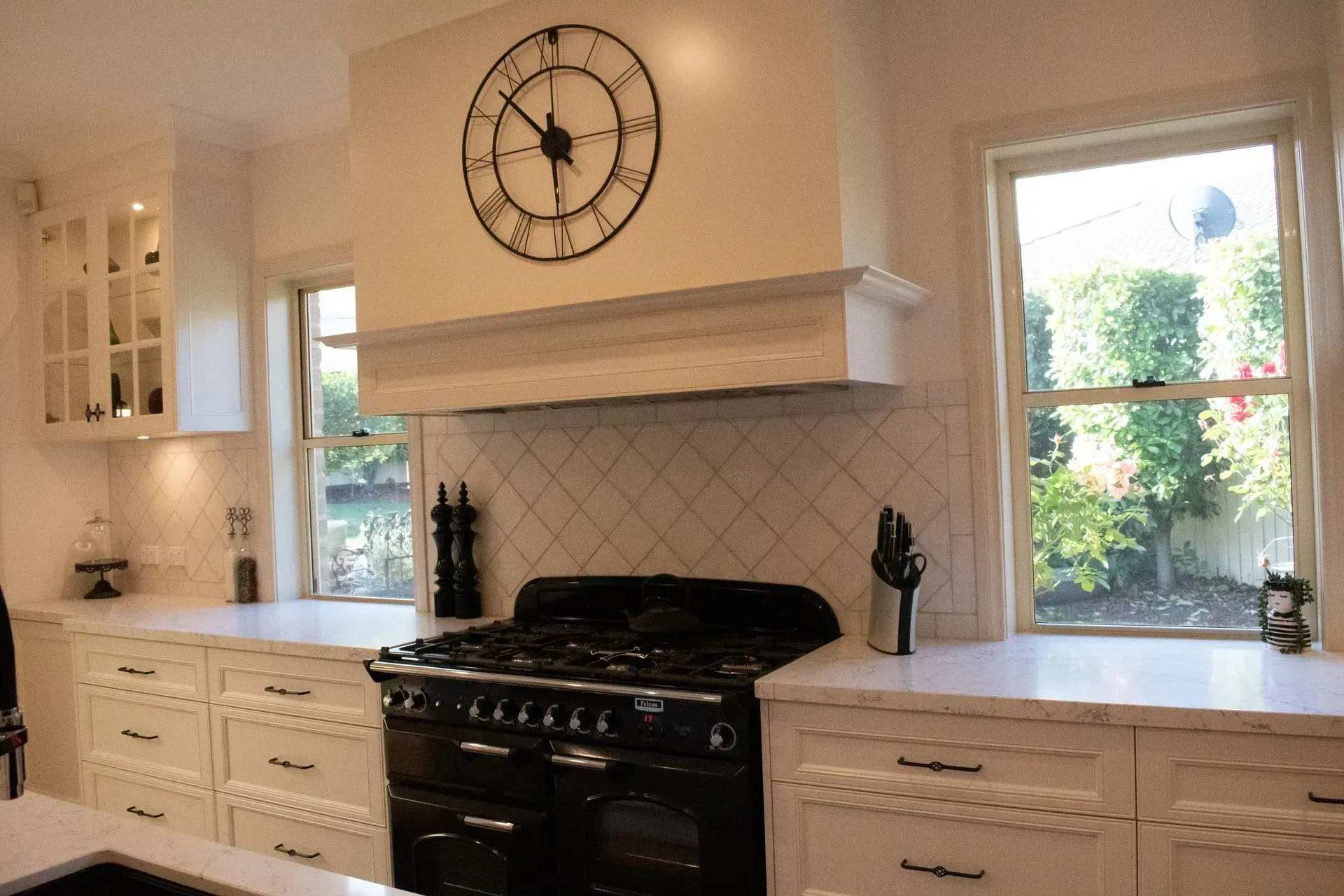 A kitchen with a clock on the wall above the stove