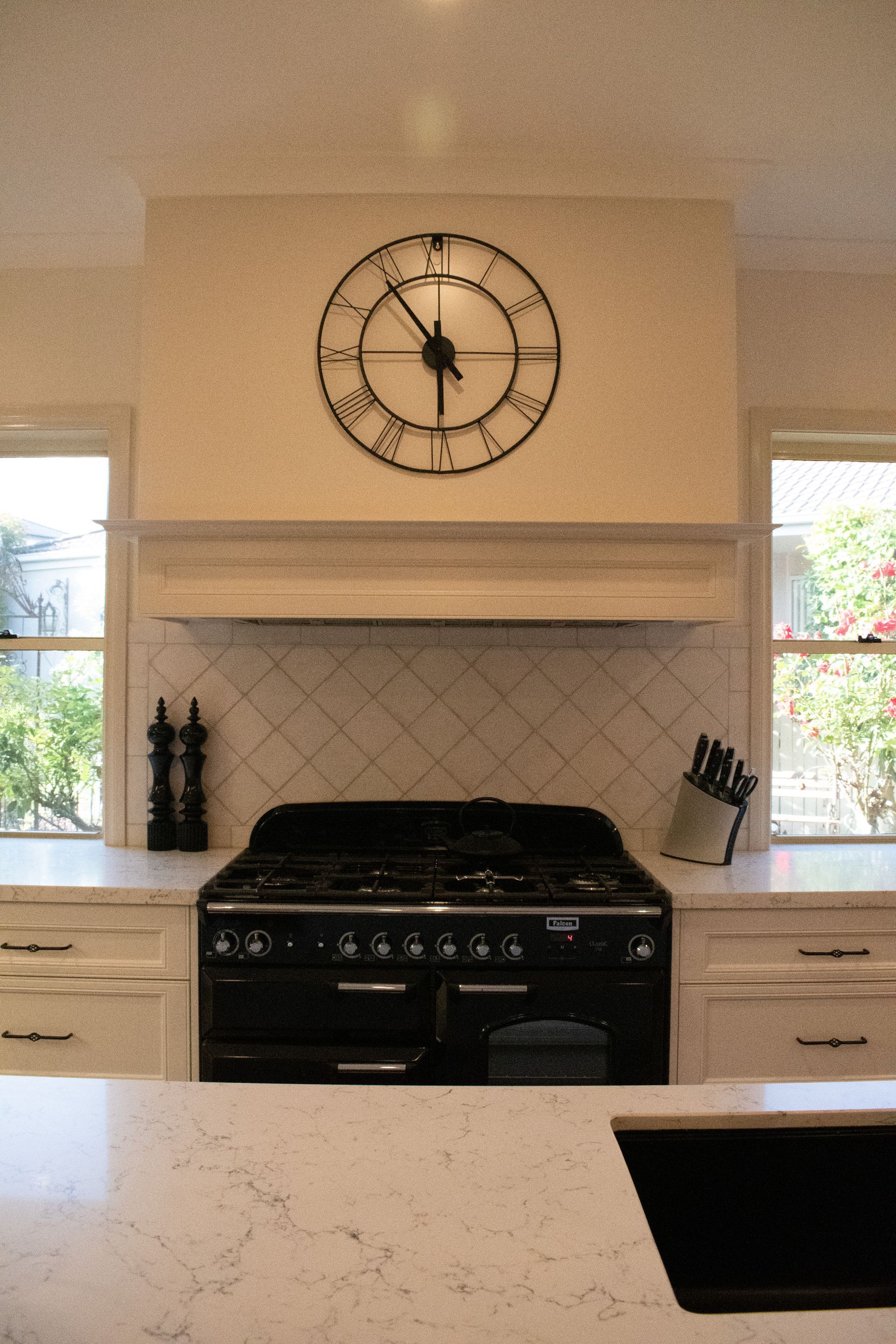 A kitchen with a clock on the wall above the stove