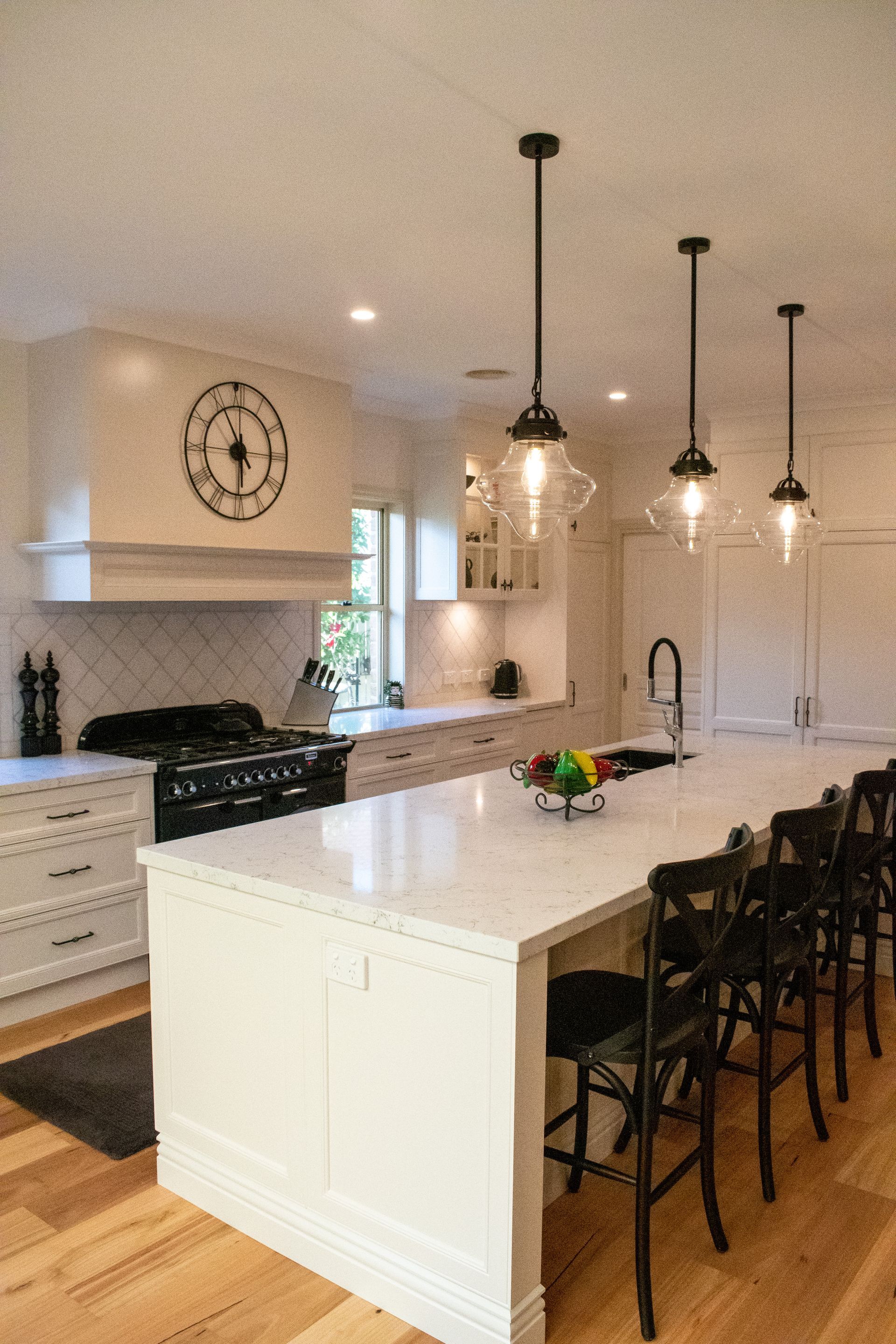 A kitchen with a large island and a clock on the wall.