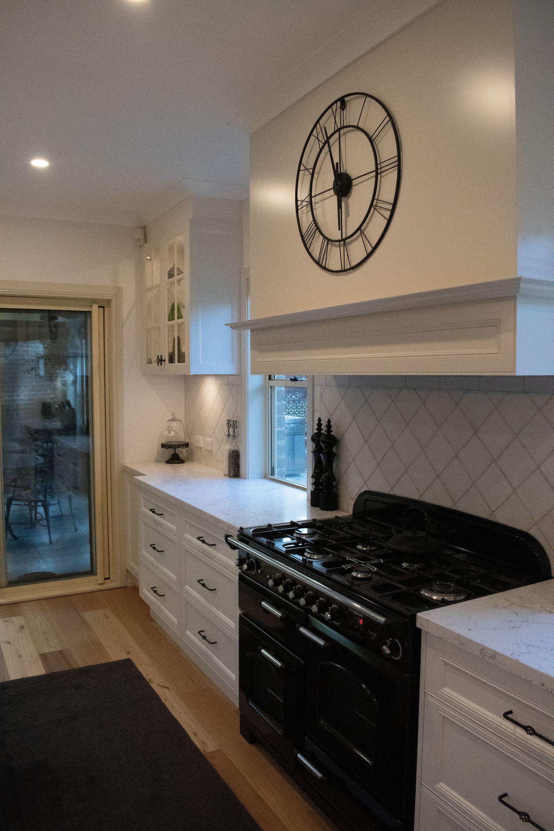 A kitchen with a clock on the wall above the stove