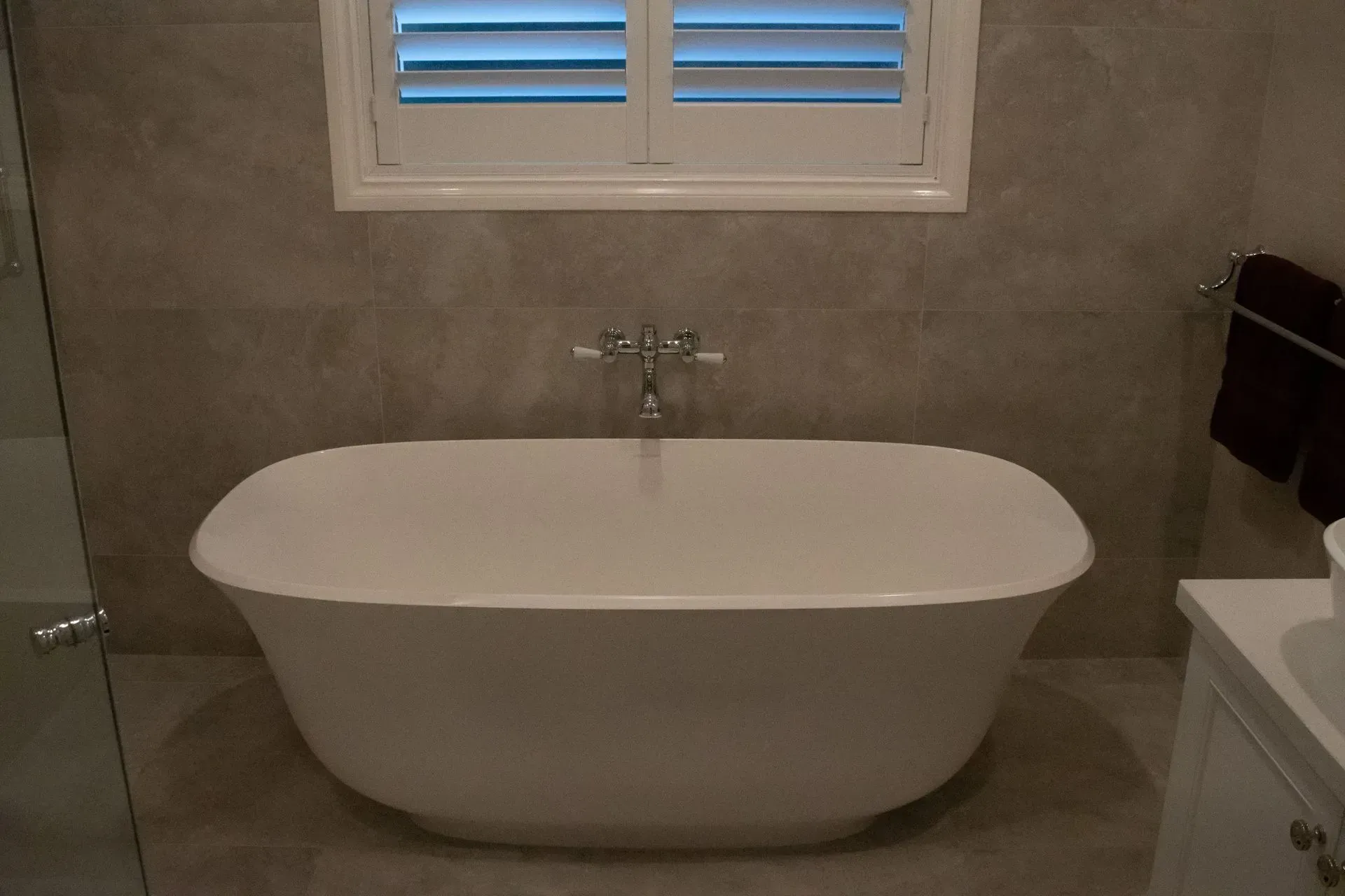 A bathroom with a bathtub and a window with shutters.