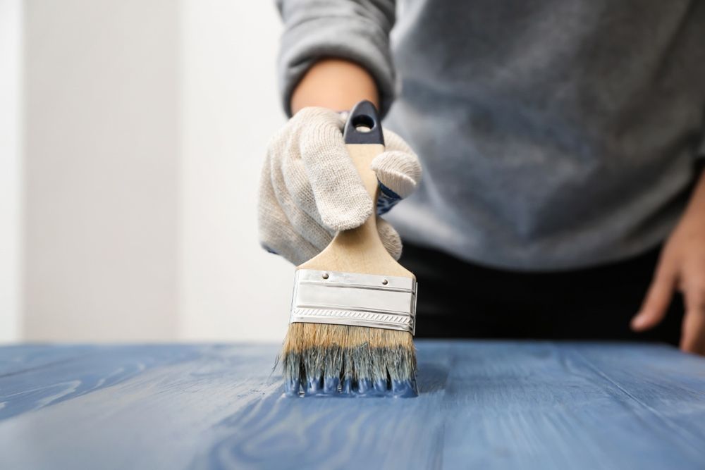 Painter Renovating Wooden Surface With Blue Colour and Brush — Professional Painters in Lennox Head, NSW