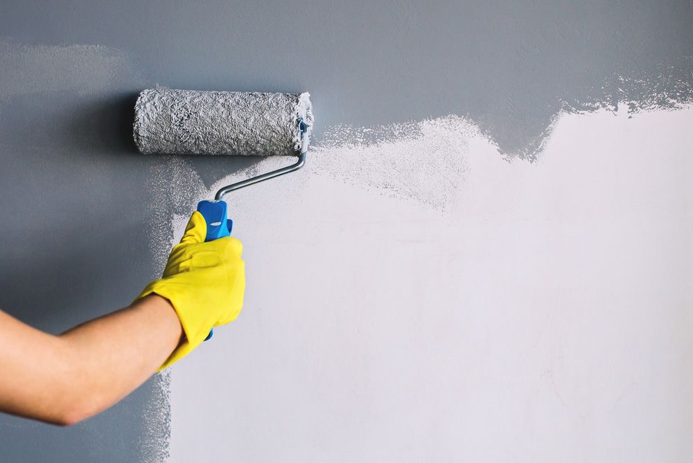 Skilled Person Painting Wall In Gray Colour with Roller — Professional Painters in Lennox Head, NSW
