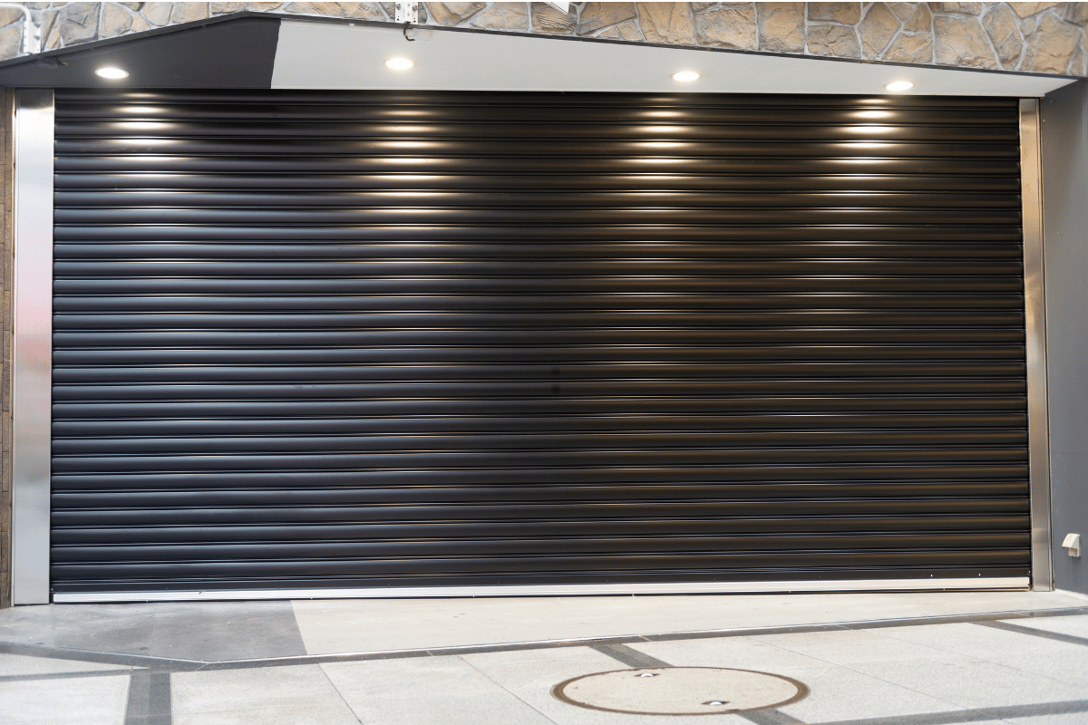 Closed black metal roll-up garage door in a building entrance