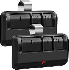 Two black garage door remote controls with silver clips and red indicator lights