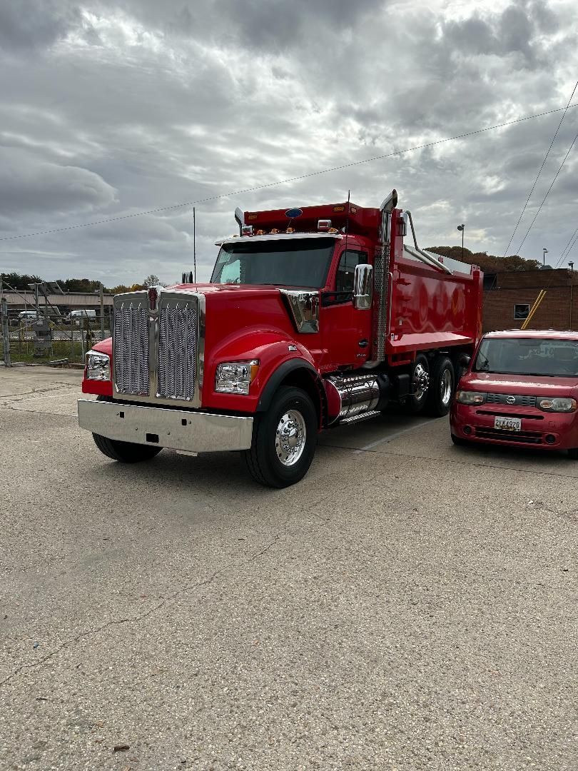 Two men are standing in front of a dump truck.